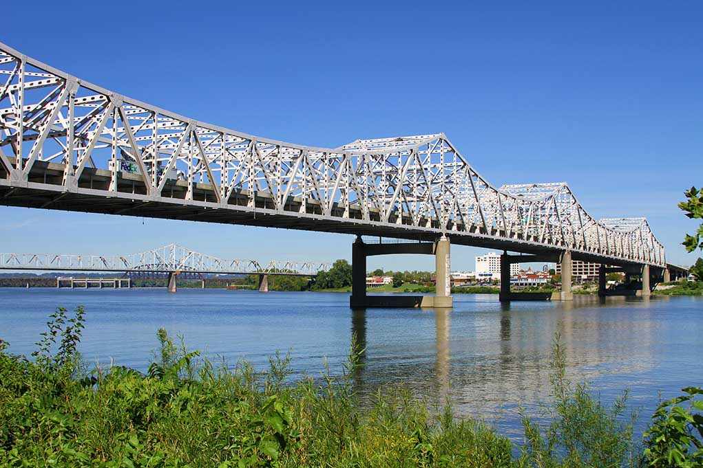 A large metal bridge spanning over a river with a clear blue sky in the background