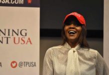 Candace Owens Issue Another OUTLANDISH Kirk Theory – Noway? A woman wearing a red cap and a white blouse speaking at a political event