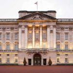Front view of Buckingham Palace with illuminated facade and British flag