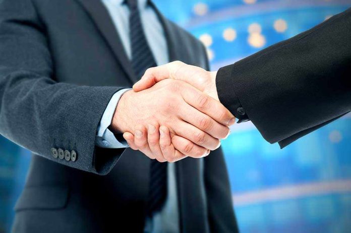 shutterstock_174221906.jpg Two business professionals shaking hands in a corporate setting