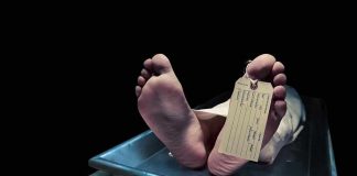 Feet of a deceased person on a coroners table with an identification tag