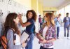 Three high school students interacting near lockers in a hallway