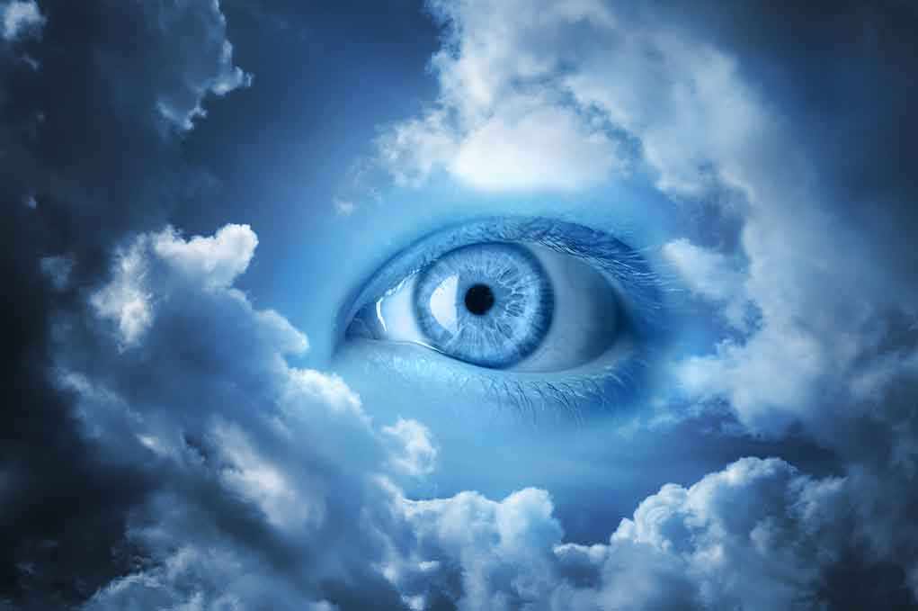 A large blue eye emerging from a cloudy sky