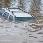 A partially submerged vehicle in floodwaters