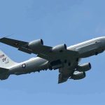 Military aircraft flying in clear blue sky.