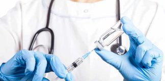 Doctor filling syringe with vaccine from vial.