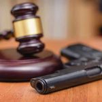 Gavel and handgun on a wooden surface.