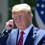 Librarian Arrested For Trump Assassination Plot Man in a suit adjusting an earpiece.