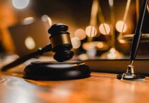 Gavel on wooden table with scales in background.