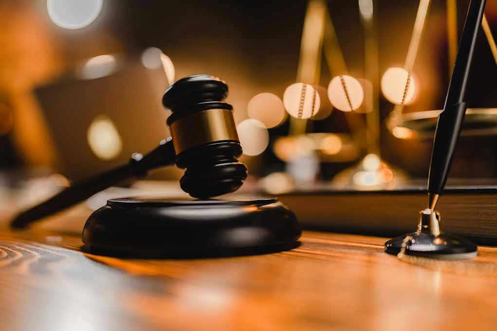 Gavel on wooden table with scales in background.
