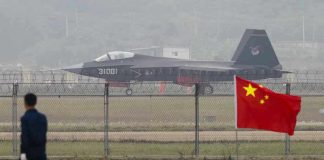 Jet with 31001 marking behind barbed wire fence.