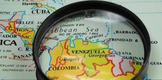 Magnifying glass focusing on Venezuela and Colombia on map.