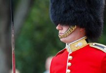 British soldier in ceremonial uniform with a black fur hat standing guard