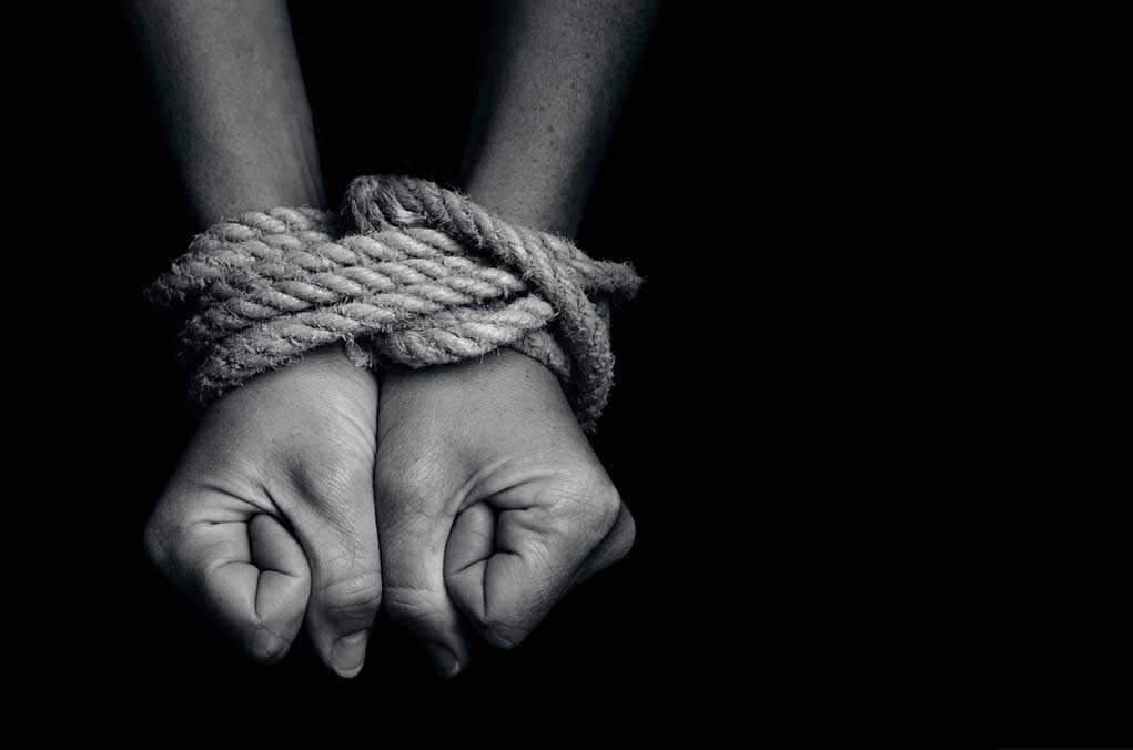 Two hands tightly bound with rope against a dark background