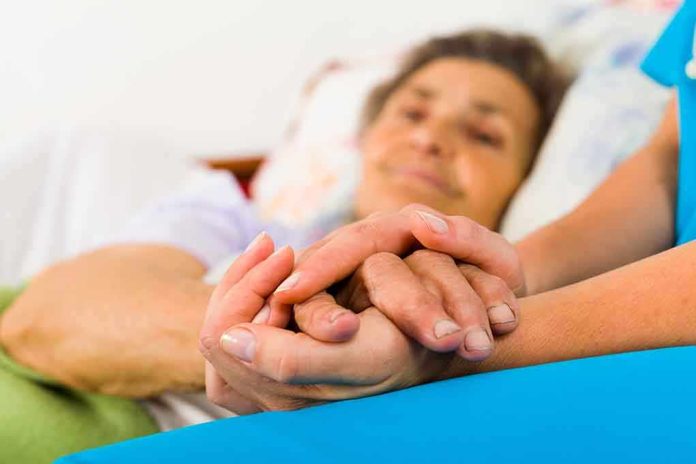 A caregiver holding the hands of an elderly patient in a hospital bed