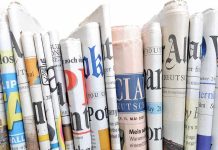 A collection of rolled newspapers displaying various headlines and designs