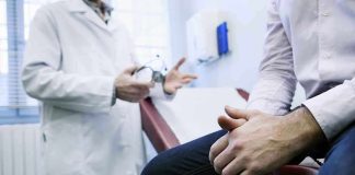 A doctor in a white coat discussing with a patient sitting on an examination table