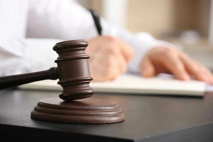 2454469737 Judges gavel on desk with person writing.