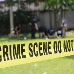 Yellow crime scene tape blocking grassy area.