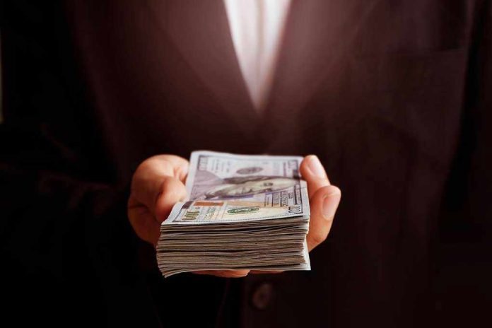 Hand holding a stack of hundred-dollar bills.