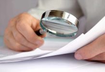 A hand holding a magnifying glass over a document