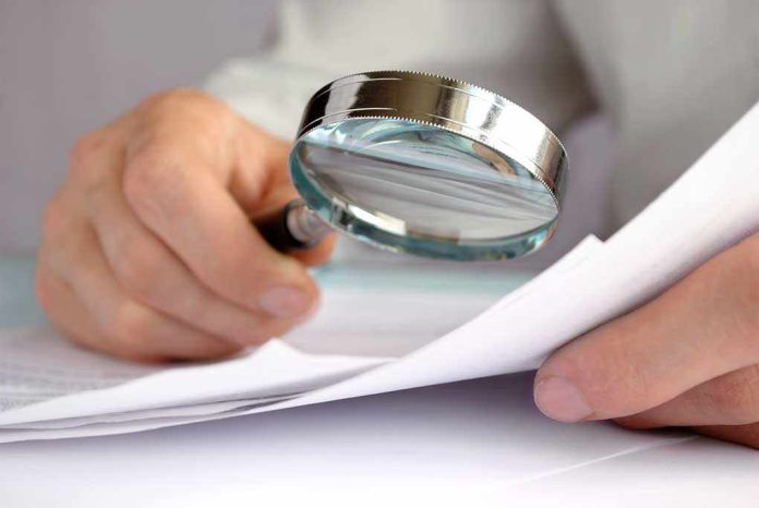 A hand holding a magnifying glass over a document