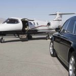 A private jet parked at an airport with a luxury car in the foreground