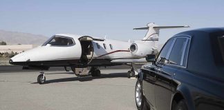 A private jet parked at an airport with a luxury car in the foreground