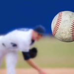 HORRIFYING Driver RAMS YOUTH Baseball Team A baseball in mid-air with a pitcher in the background preparing to throw