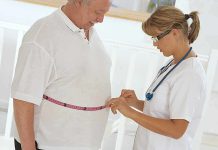 A healthcare professional measuring a patients waist with a tape measure