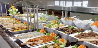 A buffet table displaying a variety of colorful dishes and salads