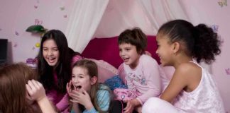 Group of children laughing and enjoying a sleepover in a cozy bedroom