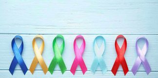 Colorful awareness ribbons on light wooden background.