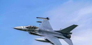 Jet fighter flying through clear blue sky.