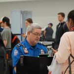 TSA Pay Freeze Sparks Democratic Outrage TSA agent checks passengers documents at airport security.