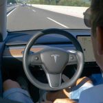 Man using autopilot mode in a Tesla car.