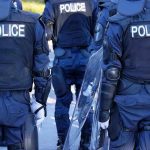Police officers in riot gear with shields.