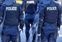 Police officers in riot gear with shields.