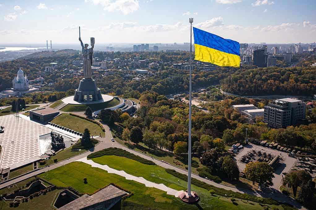 Large Ukraine flag with cityscape in background.