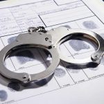 Police Volunteer’s Sickening Double Life EXPOSED Handcuffs on fingerprint form with fingerprints visible.