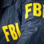 Madman Hurls Bones Over FBI Fence FBI jacket with yellow letters.
