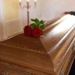 Wooden casket with red roses on top.