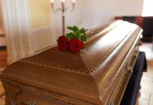 Father’s Lawsuit FREEZES Assisted Death Wooden casket with red roses on top.