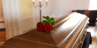Wooden casket with red roses on top.