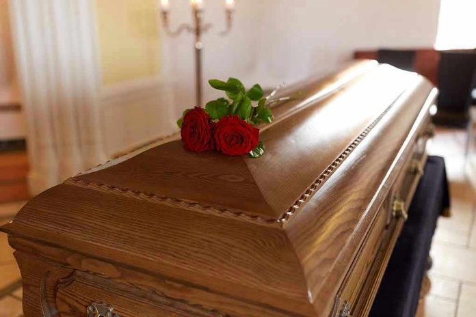 Wooden casket with red roses on top.