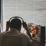 Person listening to a vintage tape recorder with headphones