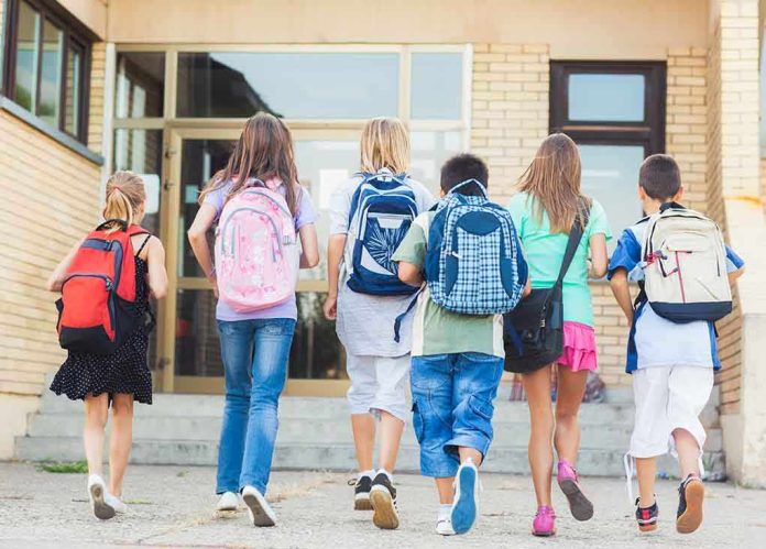 Group of children walking towards a school entrance with backpacks