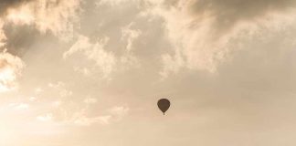 A hot air balloon floating in a cloudy sky during sunset