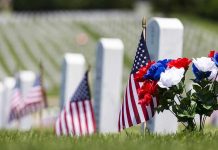 American flags and flowers placed at graves in a cemetery