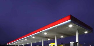 A gas station at night with illuminated fuel pumps and a convenience store